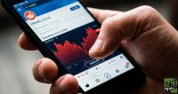 Focusing on the physical tension of a retail trader's grip on a smartphone displaying the Reddit platform creates an empathetic, high-stakes reaction for mobile users who manage their own portfolios.