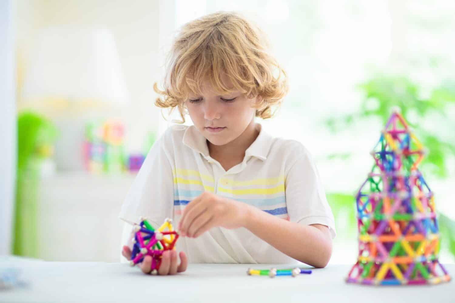 Child playing with magnetic sticks and balls building blocks. Little boy building tower. Educational toys for kids. Construction toys for young children. Geometry and math game. Preschool fun.