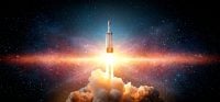 A tall, white rocket blasts off with a massive, bright orange and yellow fiery exhaust plume and smoke billowing beneath it. The launch takes place against a dark, star-filled cosmic background with a horizontal band of vibrant red, orange, and blue nebula stretching across the middle.