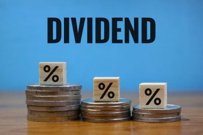Financial Dividend Concept with Percentage Cubes and Coins on blue Background