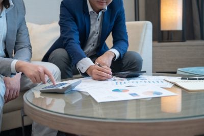 Professional financial advisor discussing personal investment strategy with Millennial Investor in a modern office, wealth management and retirement planning concept.