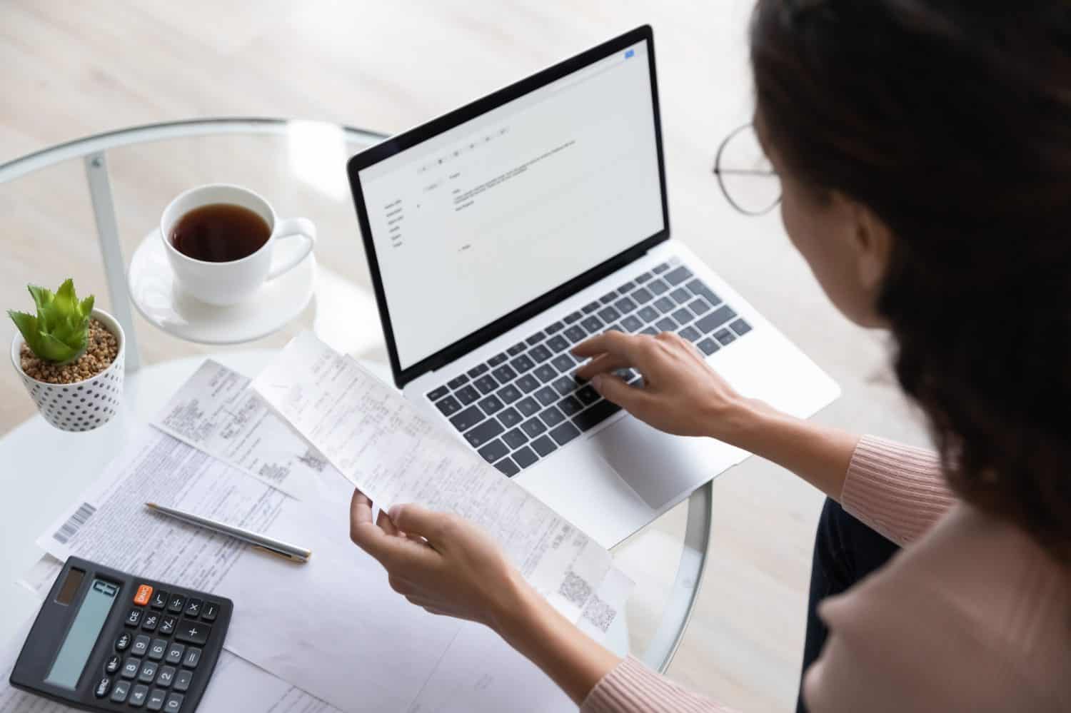 Close up top view of concentrated woman work on laptop manage family expenditures expenses using gadget, focused housewife busy calculating finances, plan budget on computer, pay bills or taxes online