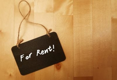 Small black chalkboard on wooden copy space background with text handwritten FOR RENT, concept of make money or earn extra income from rent out room or home or property
