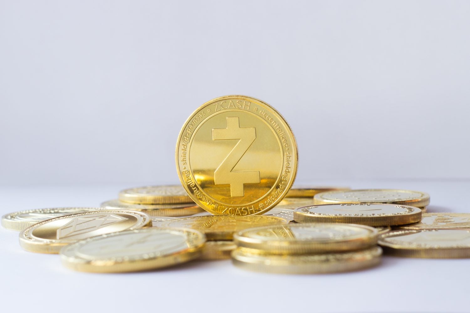 Zcash coin stand on other cryptocurrencies. Pale blue background.
