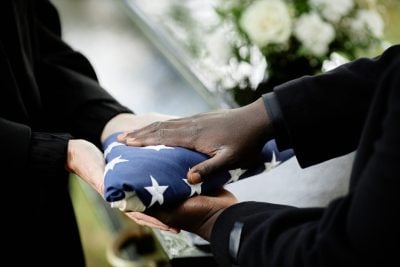 Close up of general handing folded American flag to woman at funeral ceremony for army veteran