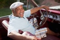Smiling older man driving convertible