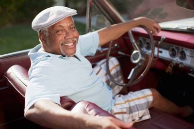 Smiling older man driving convertible