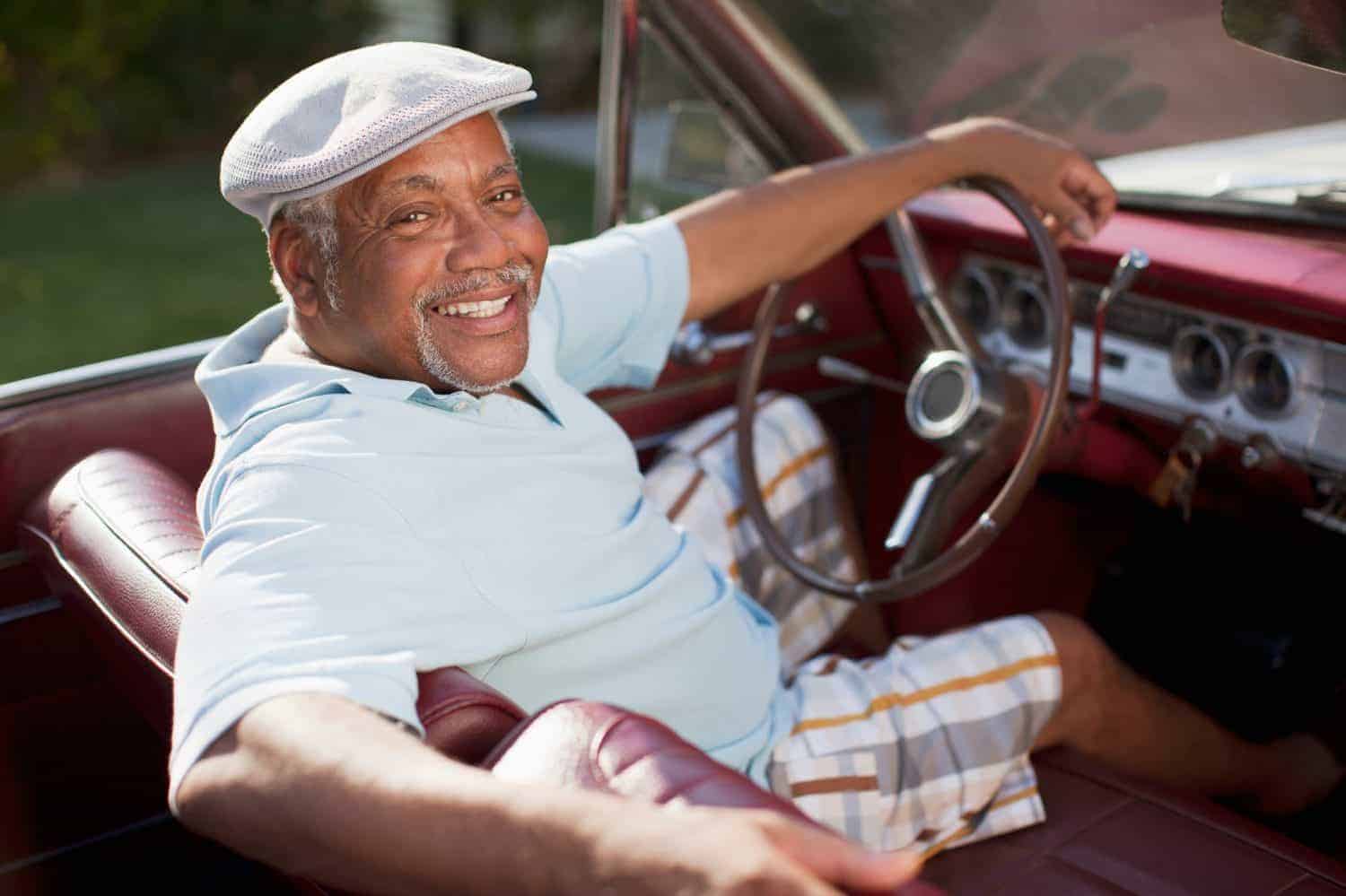 Smiling older man driving convertible