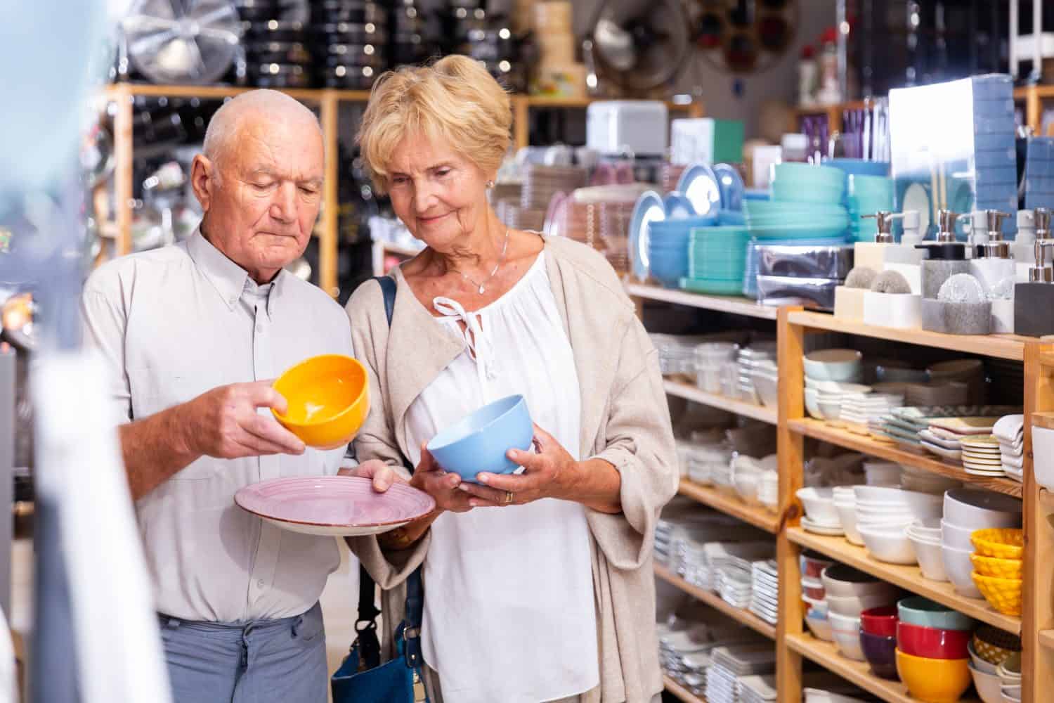 Positive couple elderly customers buying dishes in a household goods store