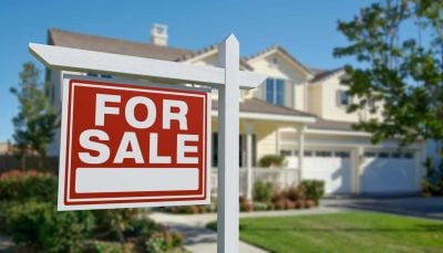 For Sale Real Estate Sign in Front of Beautiful House.