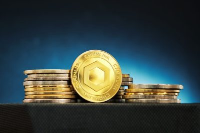A Chainlink cryptocurrency is shown in front of stacked coins, illuminated by a blue glow, creating an intriguing financial atmosphere.