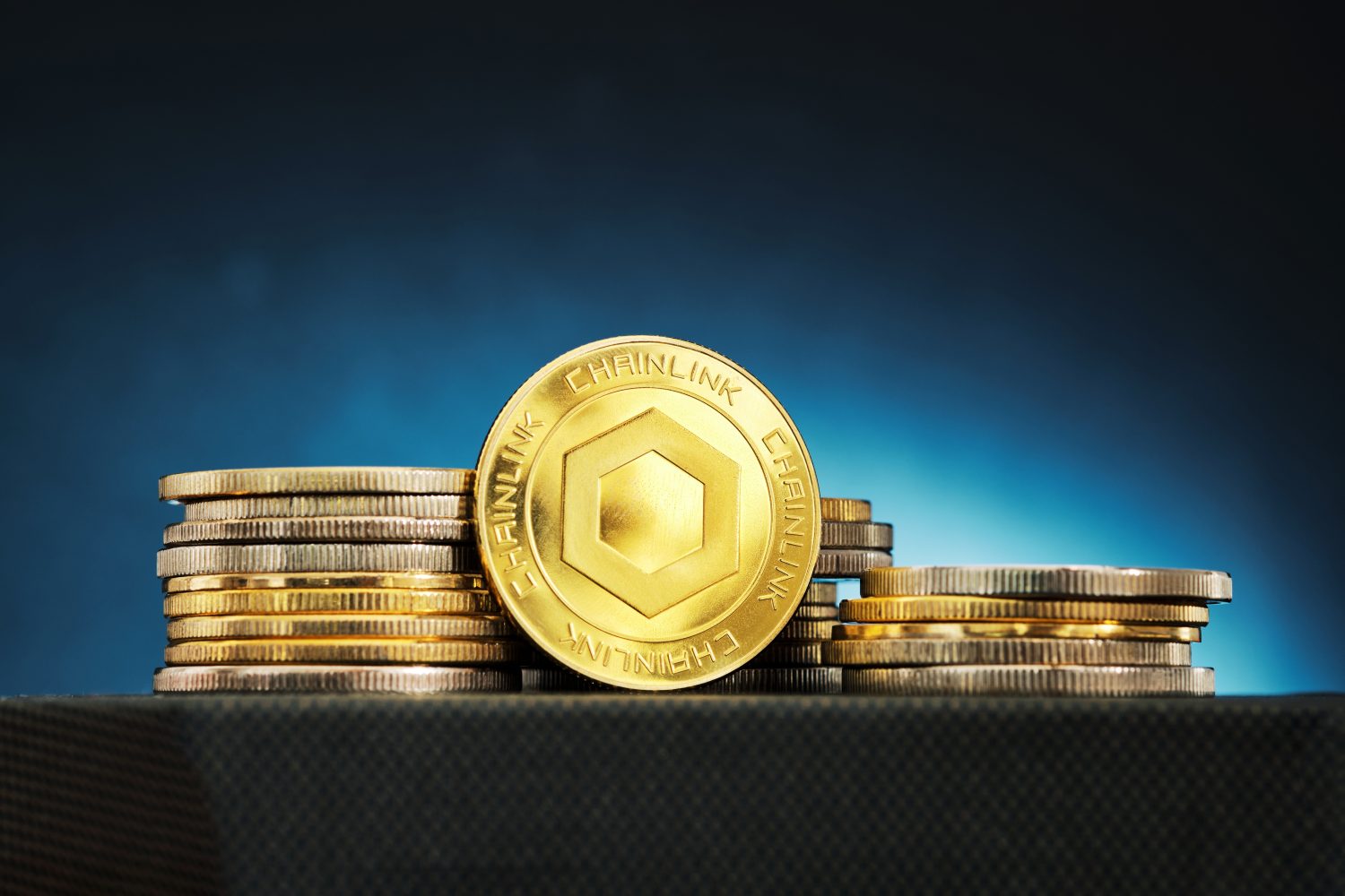 A Chainlink cryptocurrency is shown in front of stacked coins, illuminated by a blue glow, creating an intriguing financial atmosphere.