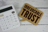 Irrevocable Trust text with calculator on wooden background