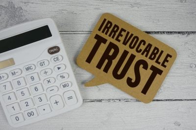 Irrevocable Trust text with calculator on wooden background