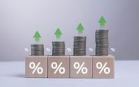 Growing stacks of coins with green upward arrows and percentage symbols represent increasing interest rates financial growth investment return inflation savings plan and positive economic performance.