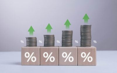 Growing stacks of coins with green upward arrows and percentage symbols represent increasing interest rates financial growth investment return inflation savings plan and positive economic performance.