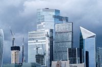 Modern glass skyscrapers in the London financial district rise across the River Thames representing contemporary urban architecture and a dynamic business city skyline.