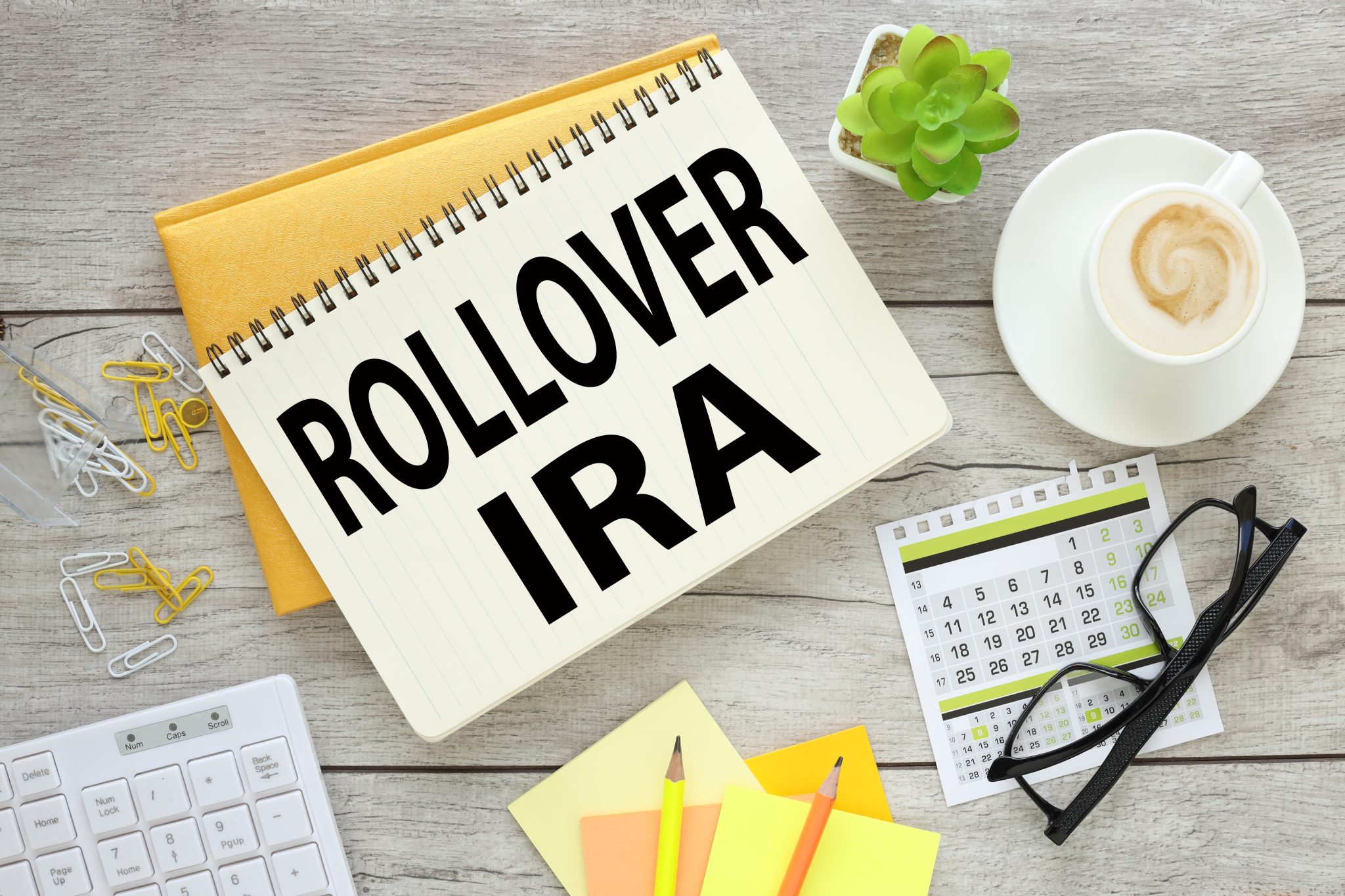 two notepads on a wooden table with text. calculator. stickers and glasses. Top view with copy space, flat lay. Rollover IRA