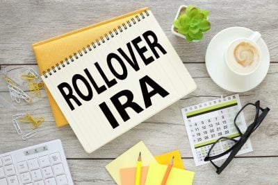 two notepads on a wooden table with text. calculator. stickers and glasses. Top view with copy space, flat lay. Rollover IRA