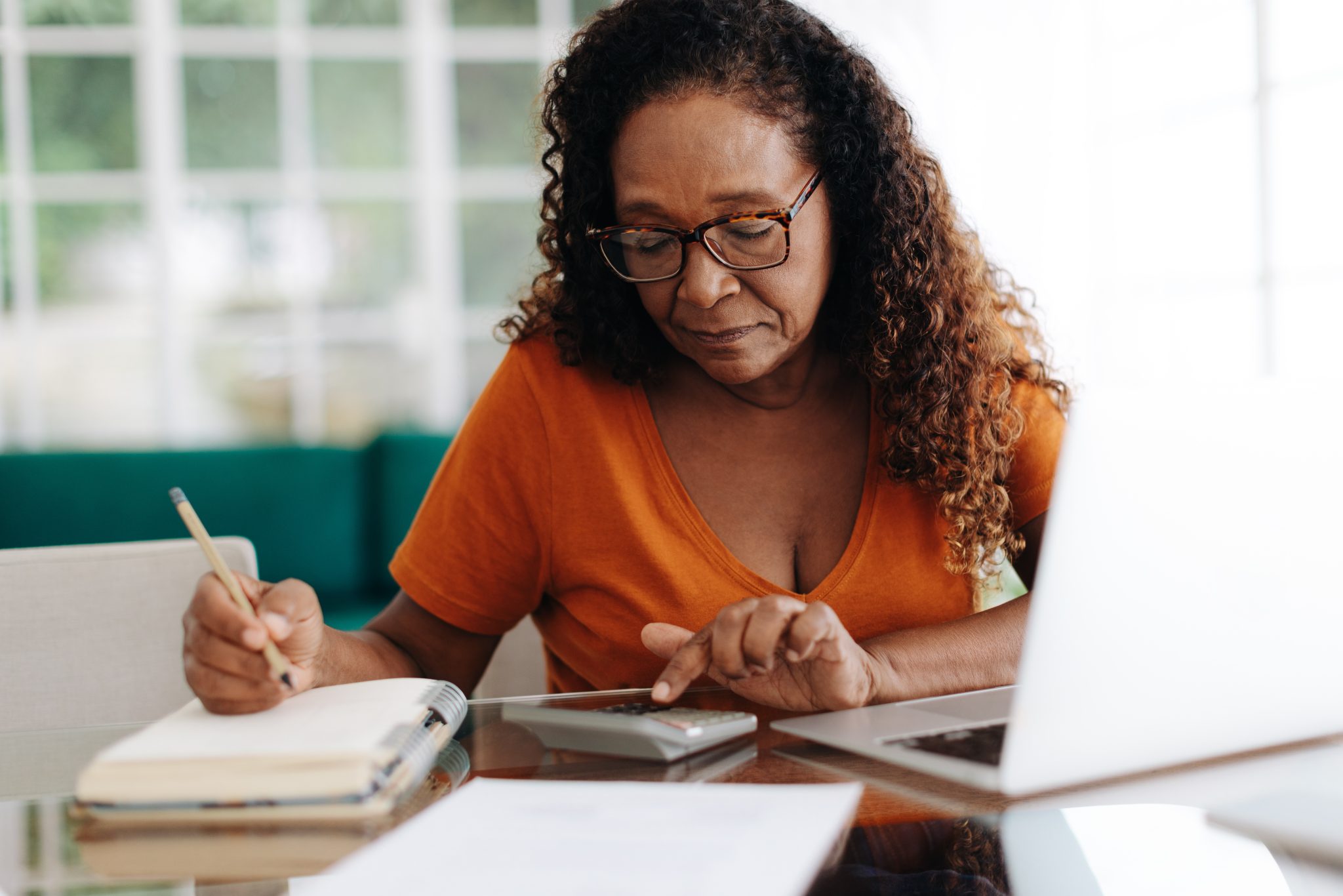 Senior woman making calculations on her retirement annuity, reviewing her pension plan and social security benefits. Elderly black woman using her financial lit