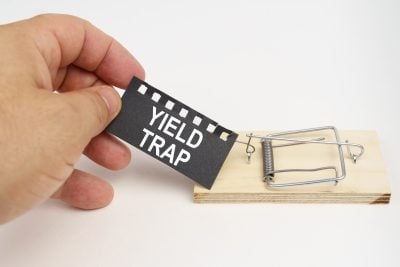 A man pulls the bait from a mousetrap. Bait, a sheet of black paper with the inscription - yield trap. Finance and law concept.