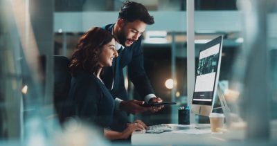 Corporate, night and technology with business people in office to search for location or venue. Collaboration, computer or tablet with smile of man and woman employee in workplace for web development