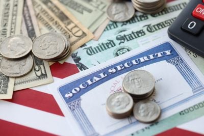 American US dollars money bills, social security number card and calculator on American flag