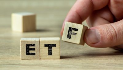 A hand arranging wooden blocks to form the acronym ETF on a light wooden surface. This image illustrates investment concepts, financial education, and stock market strategies.