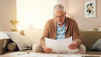Senior man, reading or finance with documents for retirement or pension fund at home. Elderly, male person or budget planning with paperwork for mortgage expenses, financial bills or invoice at house