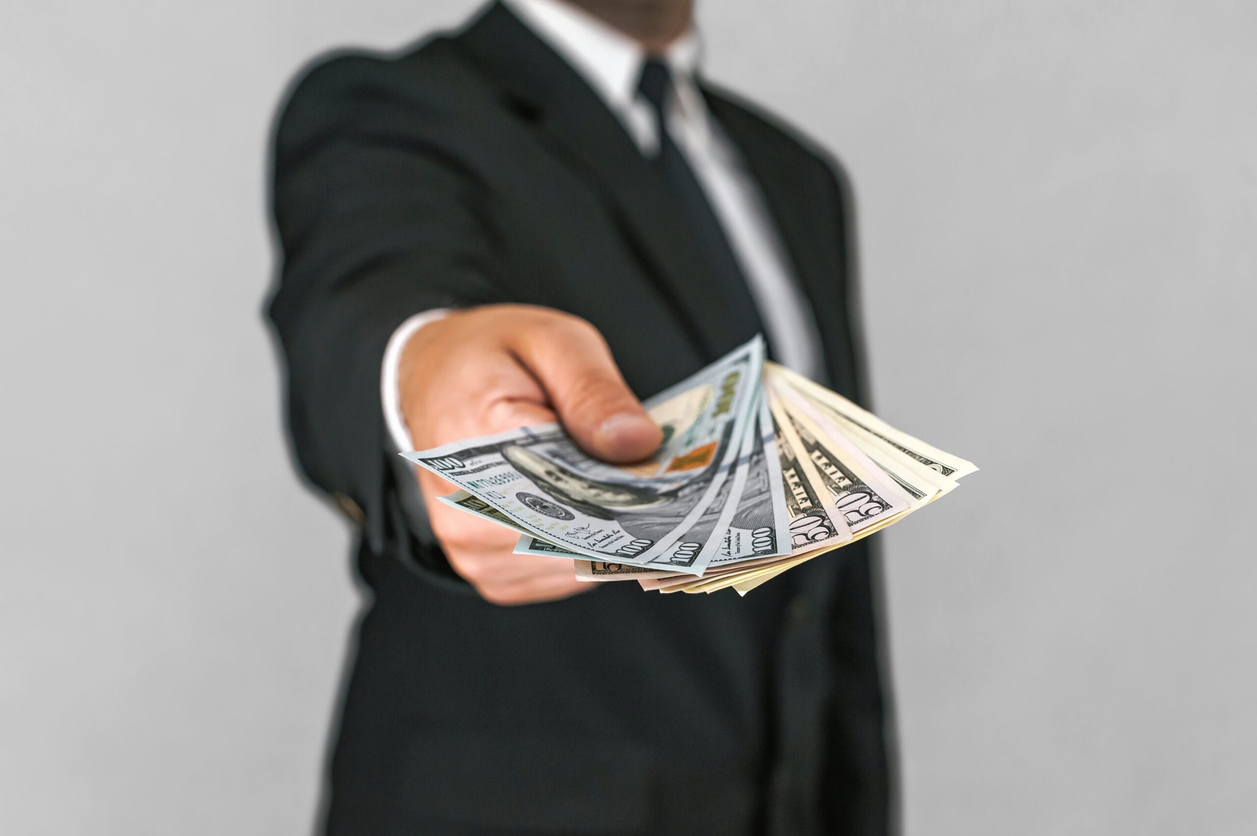 Close-up, American dollars money in the hand of a business man. White and gray background