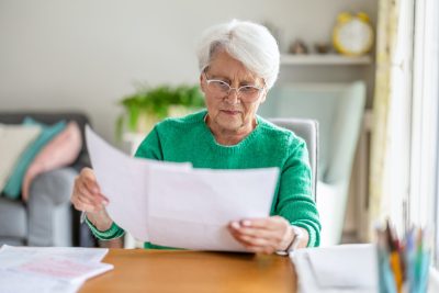 Senior woman sitting in the living room and doing paperwork