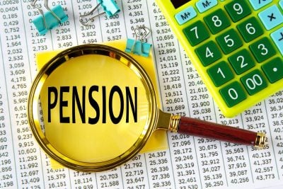PENSION - word under a magnifying glass on the background of a calculator and a sheet with numbers