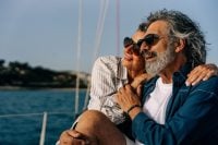 Happy senior couple embracing on a sailing yacht, enjoying affluent travel and leisure