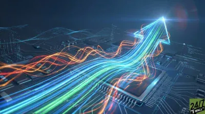 A digital image of a circuit board featuring a prominent microchip. Bright, multi-colored light trails in blue, green, and orange stream across the board, converging into a large, luminous upward-pointing arrow on the right side. Faint digital patterns are visible in the dark background, and a '24/7 WALL ST' logo is in the bottom right.