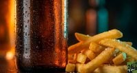 The sensory contrast between 'ice-cold' condensation on a bottle and 'salty-hot' textures of fries creates immediate tactile interest, drawing the eye to the physical reality of these stock assets.