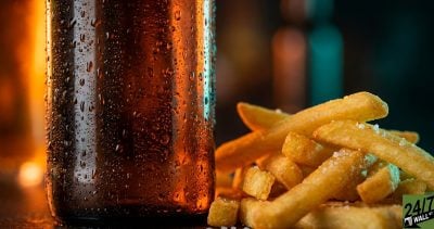 The sensory contrast between 'ice-cold' condensation on a bottle and 'salty-hot' textures of fries creates immediate tactile interest, drawing the eye to the physical reality of these stock assets.