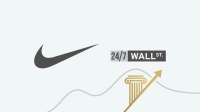A graphic on a light grey background. On the left, a dark grey Nike swoosh logo. On the right, the '24/7 WALL ST.' logo, with '24/7' in light grey on a dark grey rectangle, and 'WALL ST.' in white on a black rectangle. Below, a golden architectural column with a capital and fluted shaft, and a golden arrow pointing upwards and to the right, are overlaid on two wavy grey lines.
