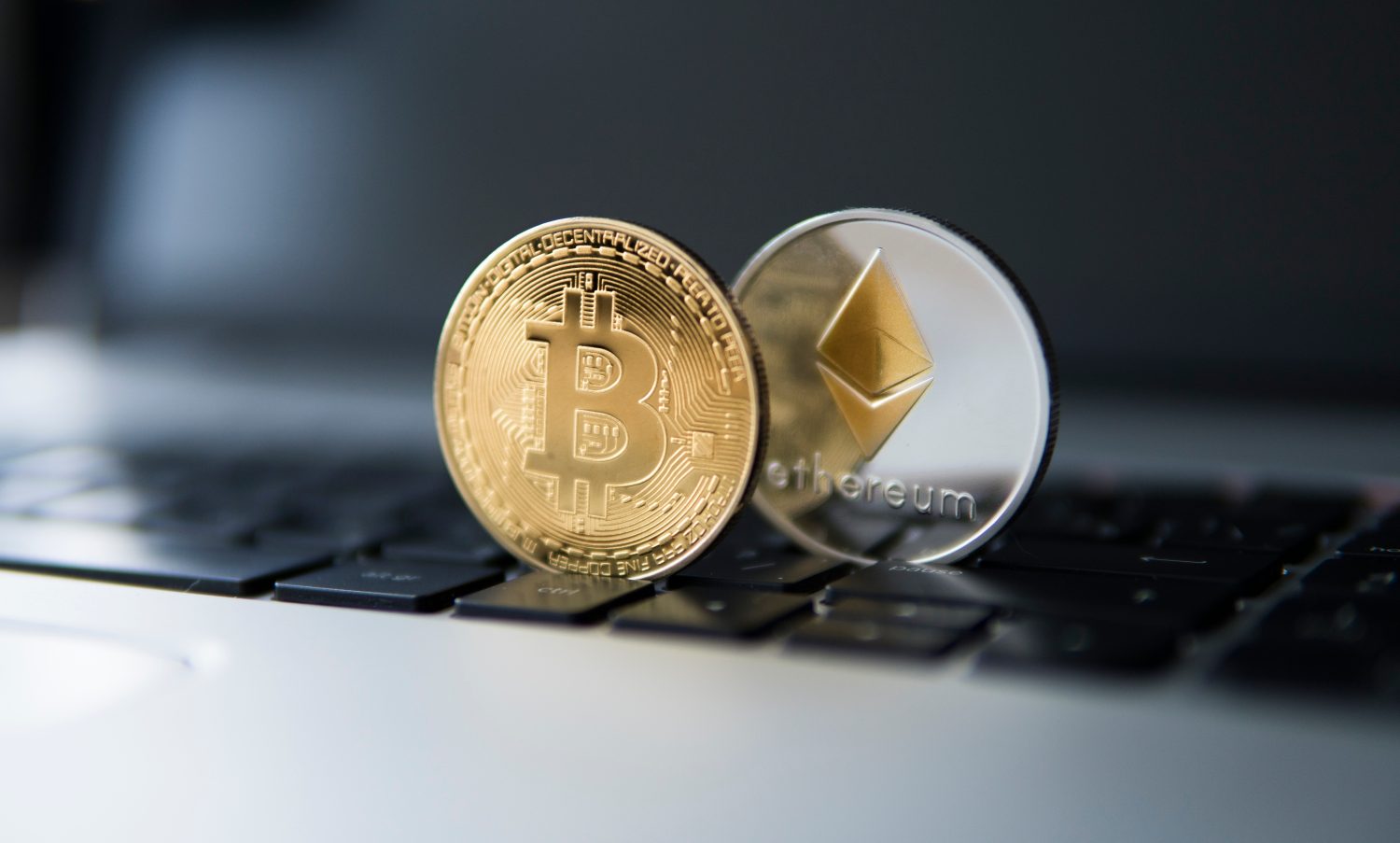 Golden bitcoin and Ethereum coins on a laptop. Crypto currency on a computer black keyboard. Digital currency. Virtual money. Metal coins of bitcoin. Bussiness, commercial, Exchange. Digital Money.