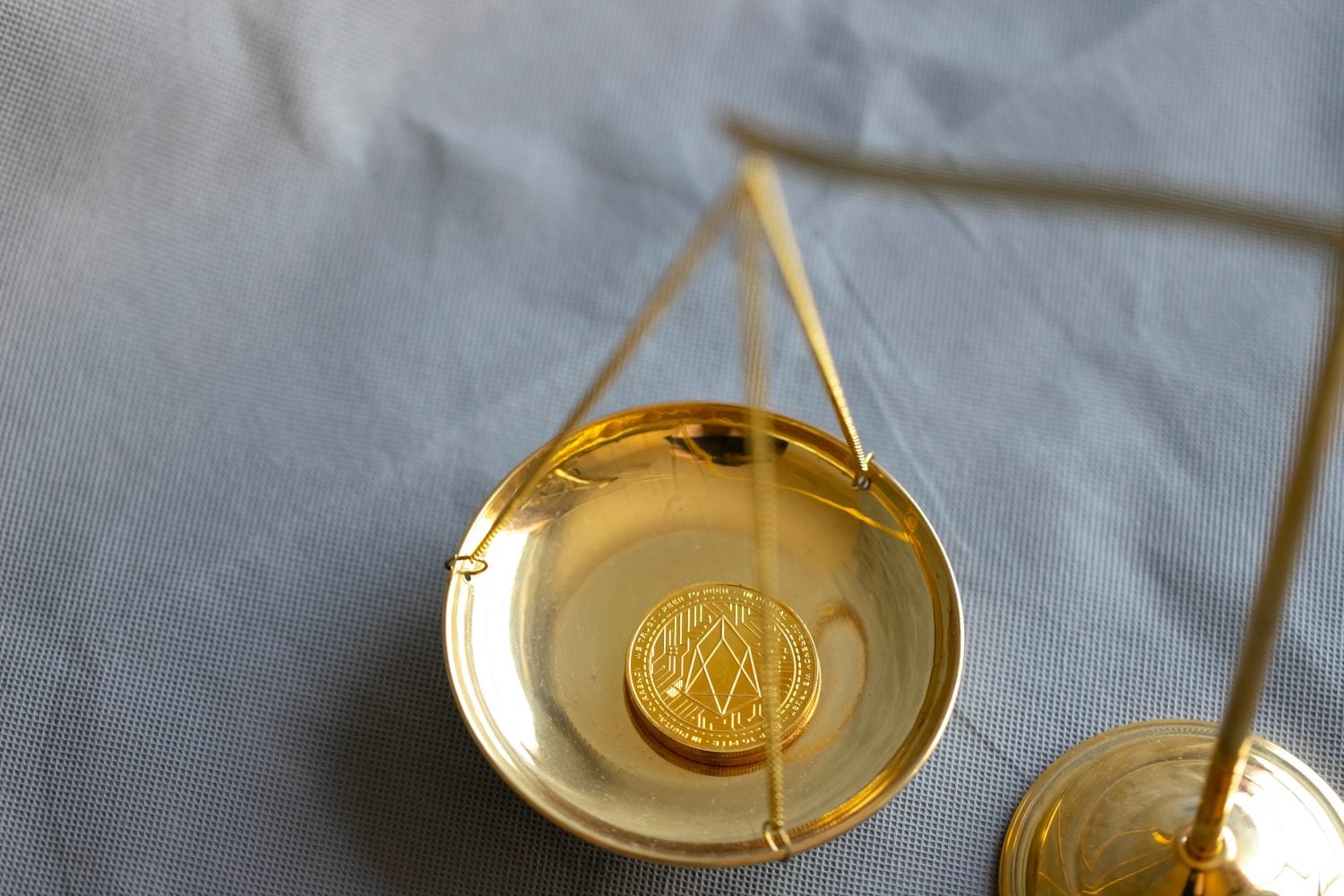 EOS cryptocurrency coin on judge balance scales. Disputes connected with EOS cryptocurrency concept.