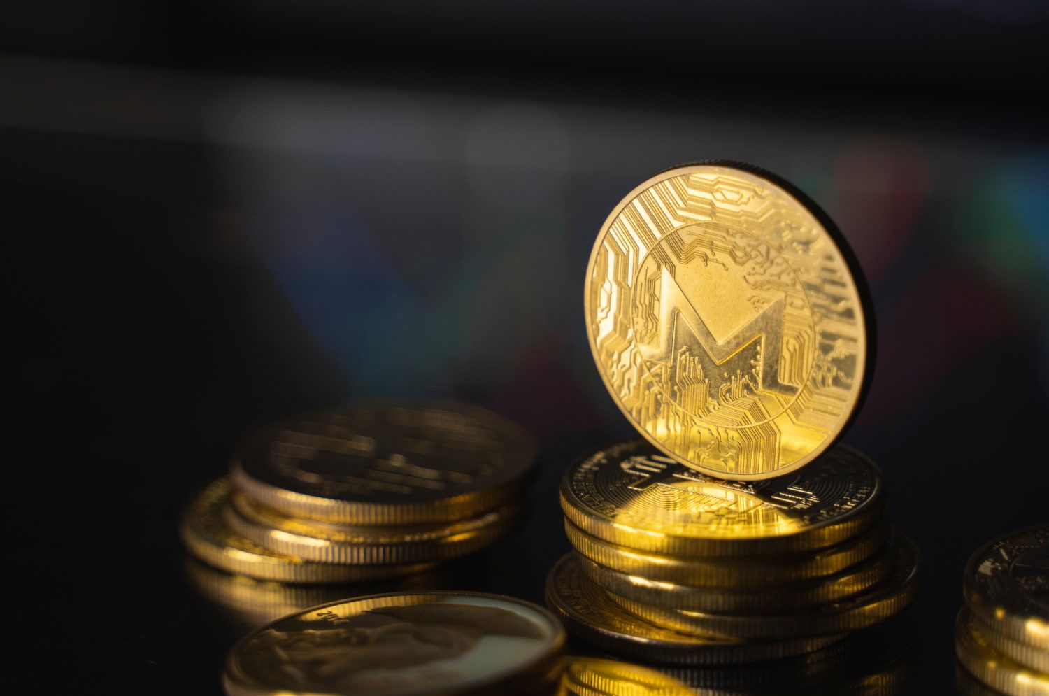 Monero and virtual money concept. Gold monero bitcoins on a stack of coins with chart of growing and falling valuance of a cryptocurrency. Mining or blockchain technology.