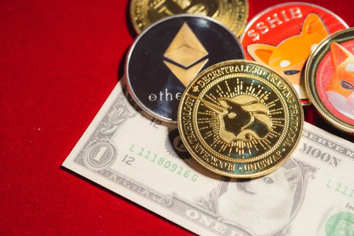 A close-up photograph of several cryptocurrency coins and a one-dollar bill on a vibrant red surface. A gold Uniswap coin with a unicorn emblem is centered, flanked by a silver and black Ethereum coin. Behind them are red Shiba Inu coins, and a portion of a US one-dollar bill is visible beneath the coins.