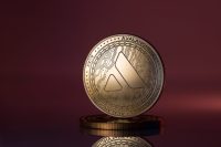 Avalanche AVAX Cryptocurrency Physical Coin Placed on reflective surface and lit with red and purple lights.