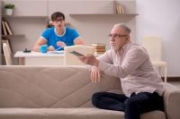 Young male student and his grandfather at home
