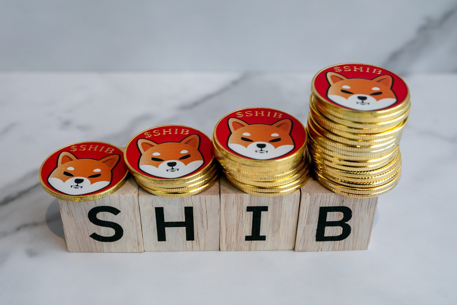 Many of Shiba inu coins (SHIB) are on wooden blocks with a white marble background.