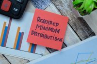 Concept of Required Minimum Distributions write on sticky notes isolated on Wooden Table.