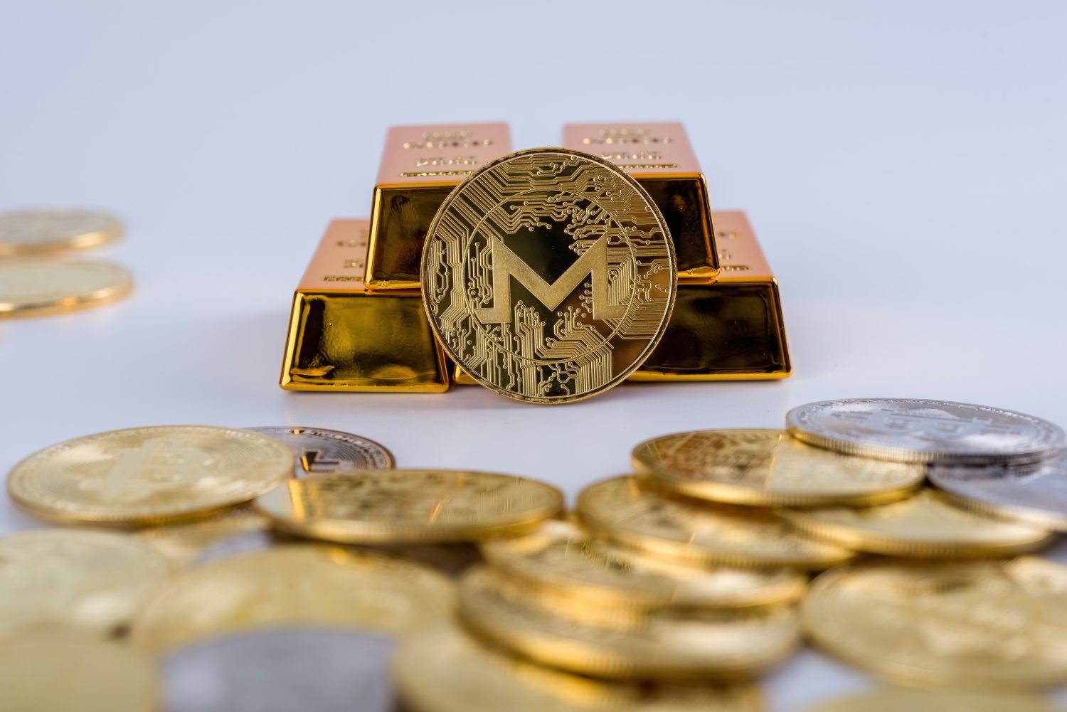 Cryptocurrency concept. Shining Monero cryptocurrency coin in front of five gold bars, isolated in white background. selective focus.