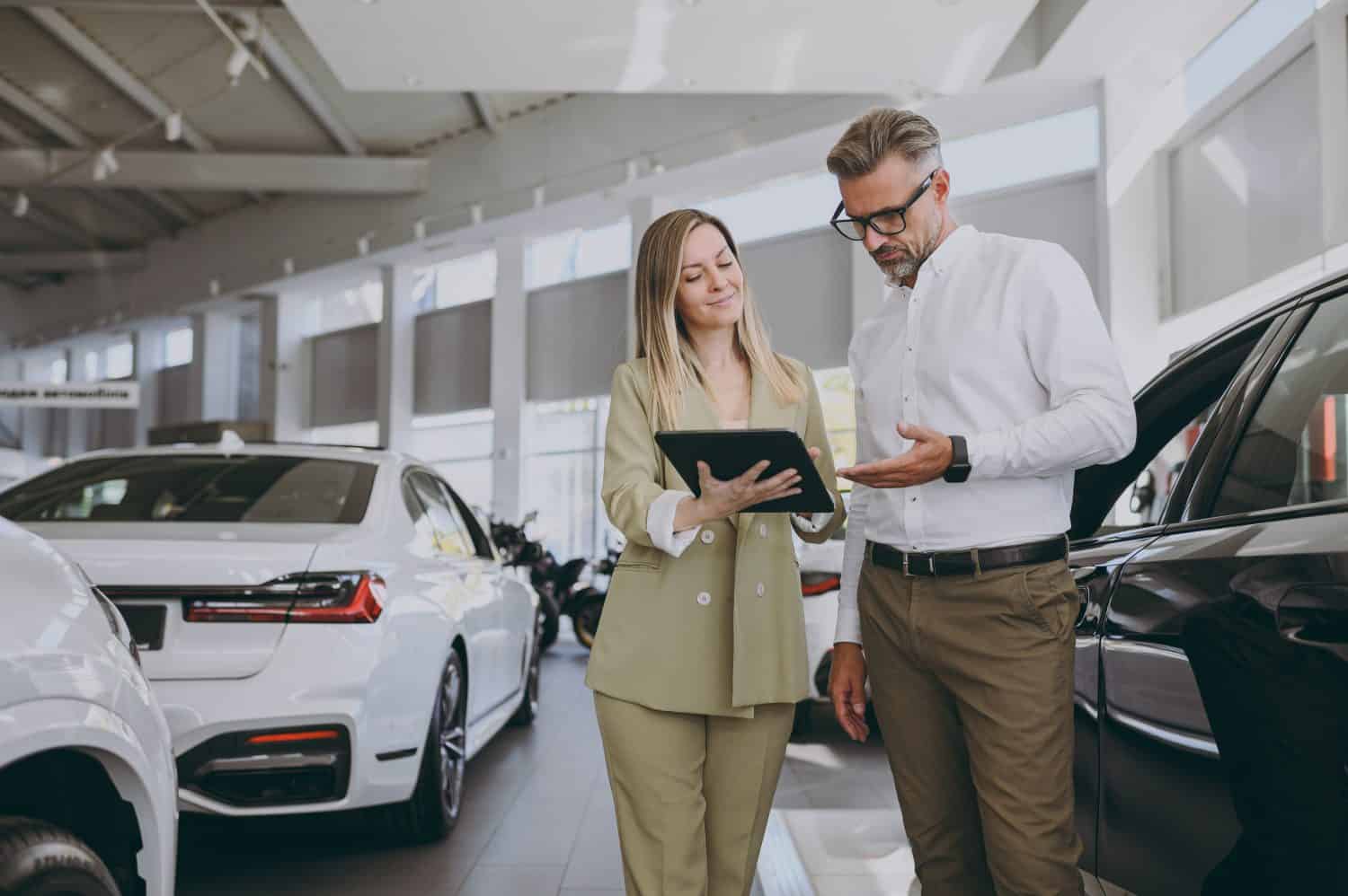 Adult man customer male buyer client wearing shirt consult with salesman signs documents choose auto want to buy new automobile in car showroom vehicle salon dealership store motor show. Sales concept