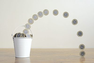 Pound Coins Filling A Metal Bucket. Saving Money Concept.