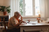Elderly woman looking sadly at few banknotes on table. Concept of financial concerns for seniors.