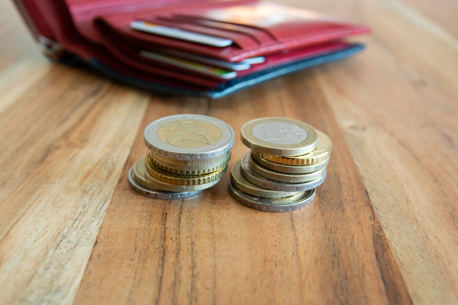 Coins stack on the wood table near the leather partmone. Wallet with european money for commerce business concept.